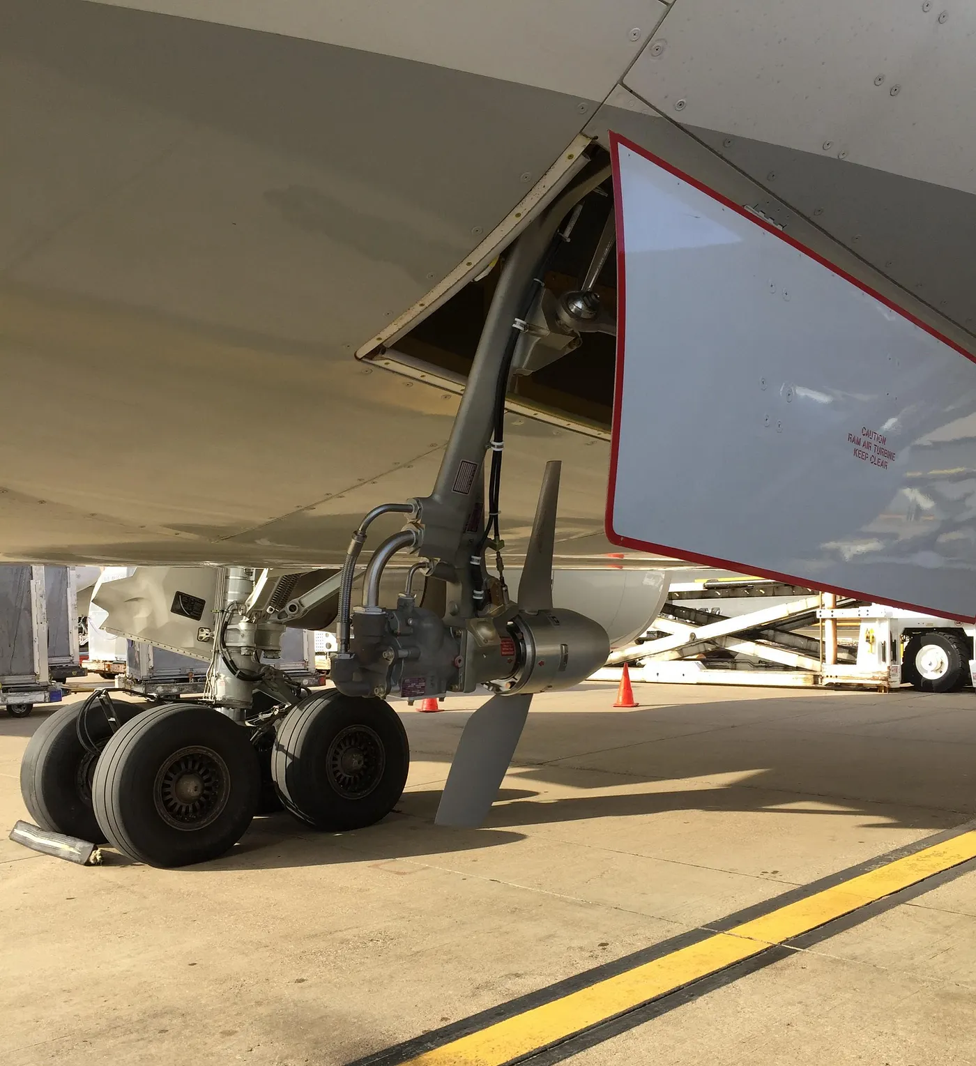 A Ram Air Turbine deployed from the belly of a commercial aircraft, showing the two-blade propeller and hydraulic pump assembly